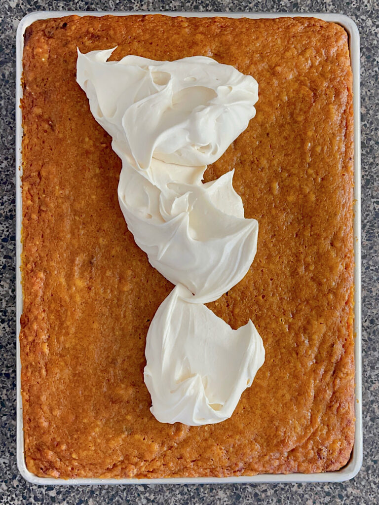 Cream cheese frosting dolloped on a pan of pumpkin bars.
