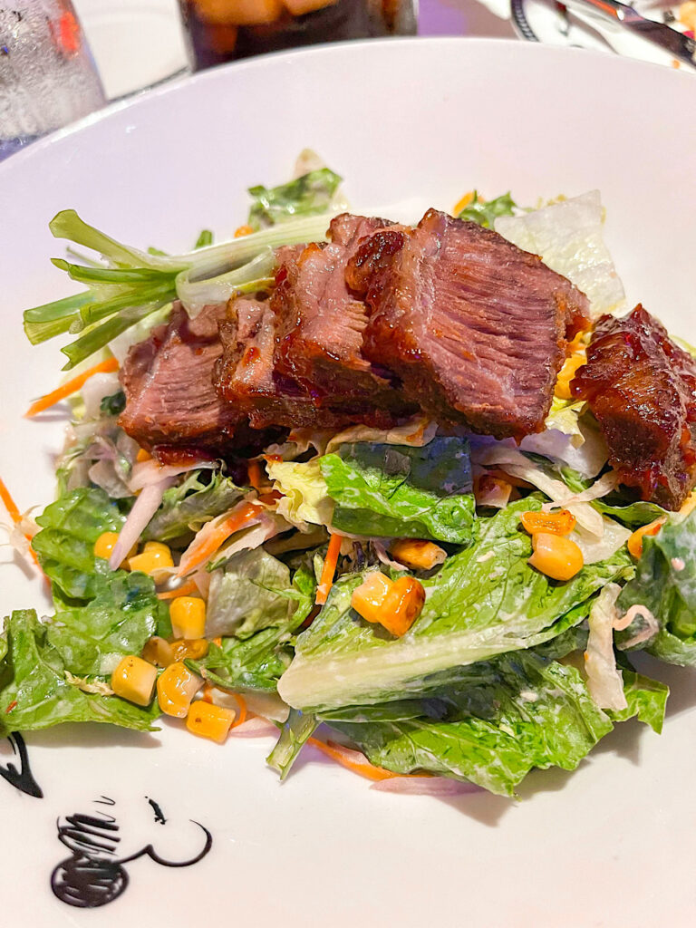 Braised Barbecue Beef Rib Salad- Slowly Braised Barbecue Beef Rib with Romaine Leaves, Spinach, Macadamia Nuts, Carrots, Roasted Corn Kernels and Shallots served with Cornbread and a Tomato Sour Cream Dressing from Pirate Night on the Disney Magic.