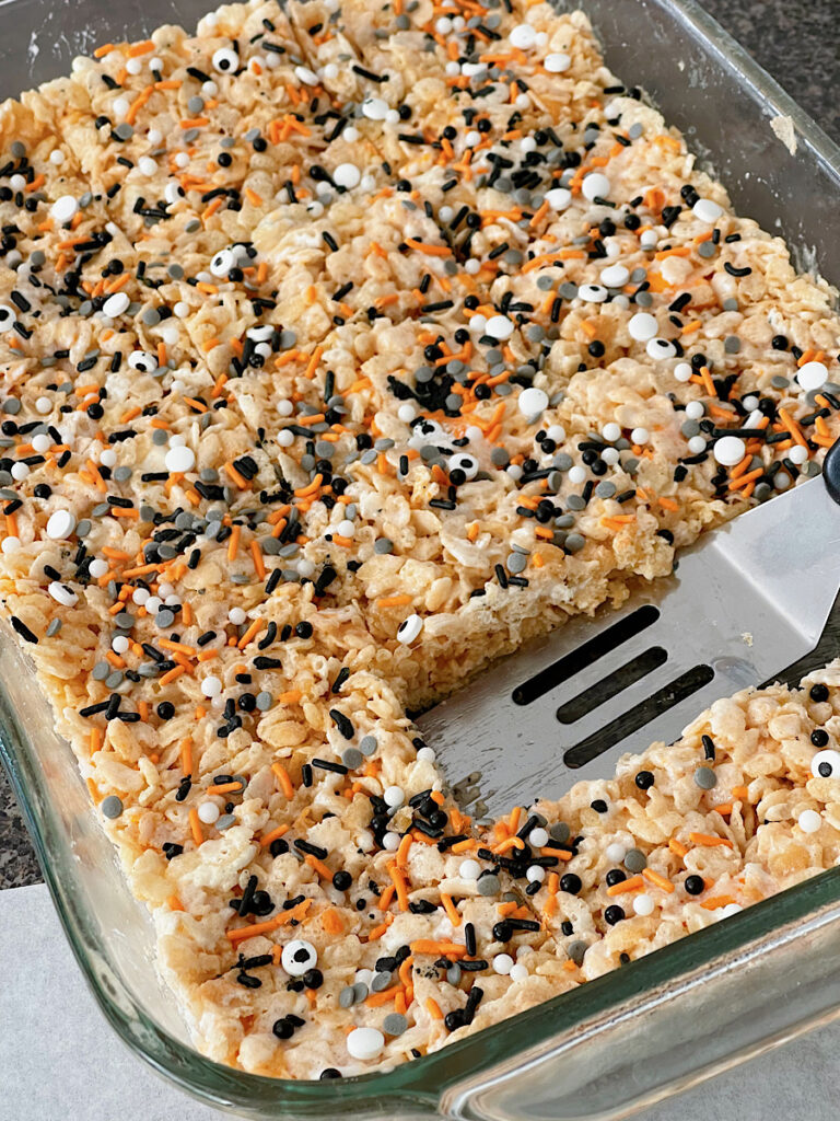 A pan of Halloween Rice Krispie Treats cut into squares with a spatula.