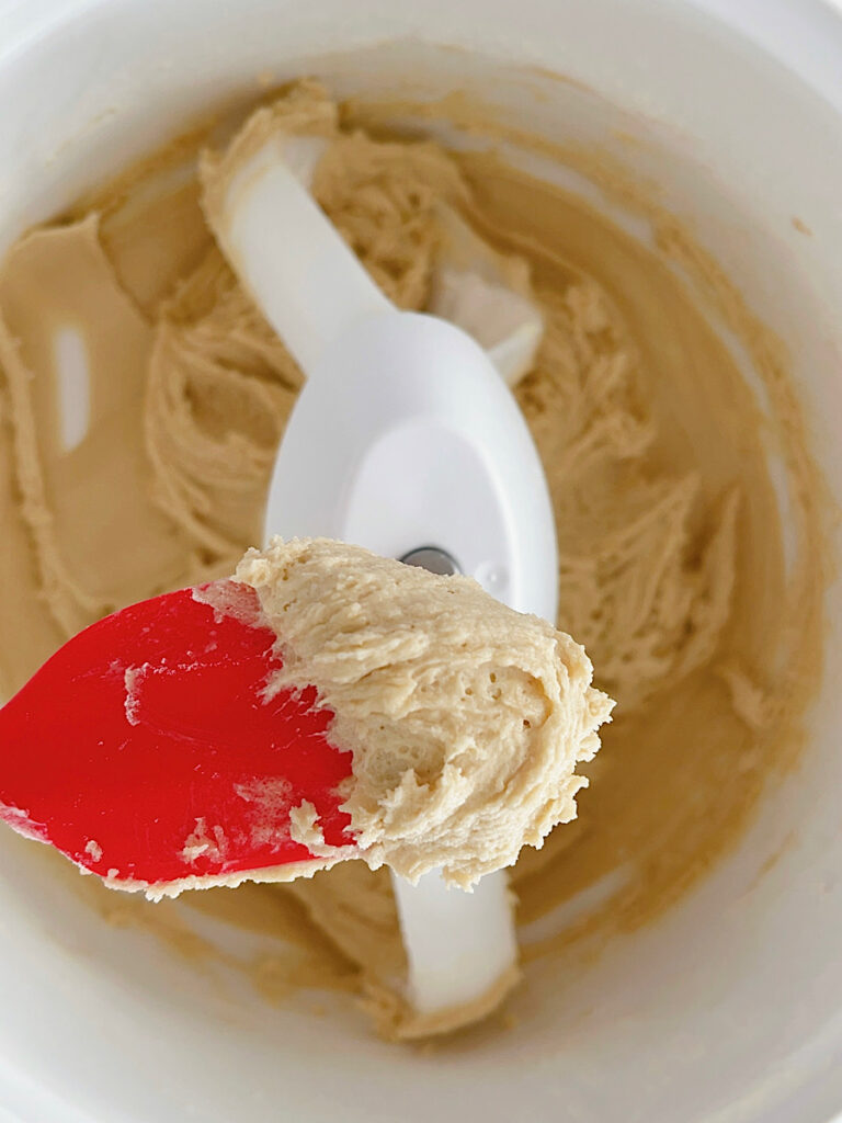 Cookie dough in a stand mixer with a red spatula.
