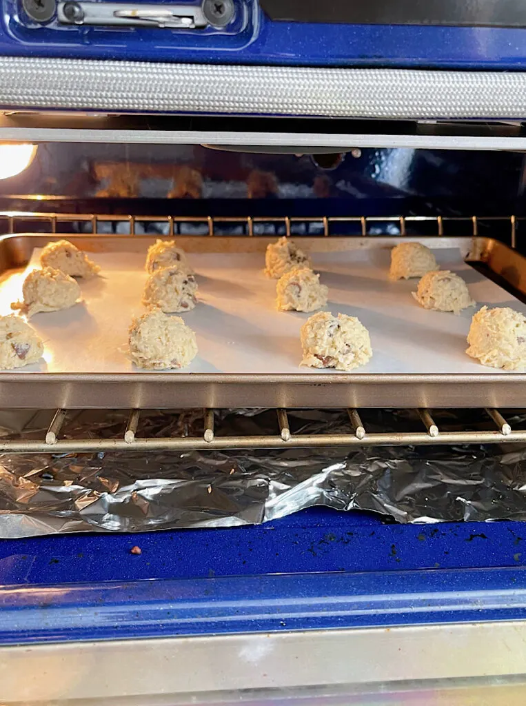 Almond joy cookie dough on a baking sheet in an oven.