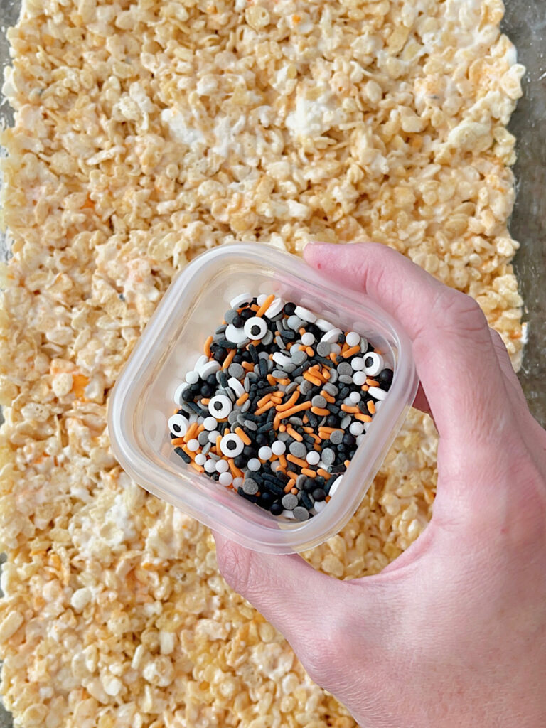 A cup of Halloween sprinkles and a pan of rice krispie treats.