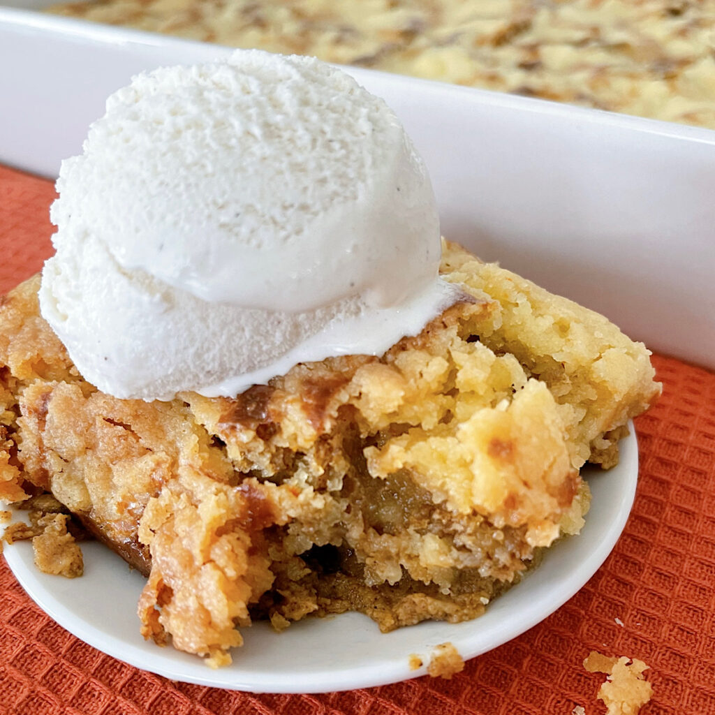 A slice of pumpkin cobbler with a scoop of vanilla ice cream.