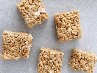 Pumpkin Rice Krispie treats cut into squares on parchment paper.