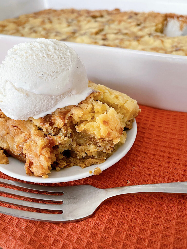 A slice of pumpkin cobbler with a scoop of vanilla ice cream.