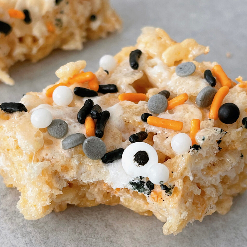 A Halloween Rice Krispie Treat with sprinkles missing a bite.