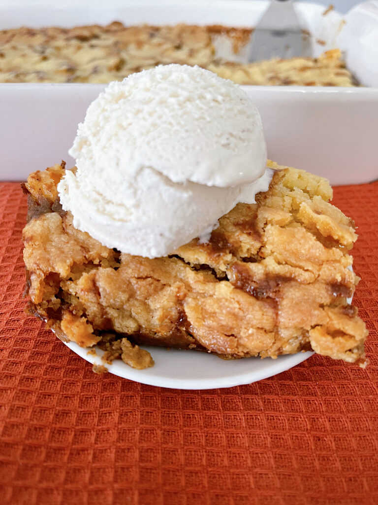 A slice of pumpkin cobbler with a scoop of vanilla ice cream.