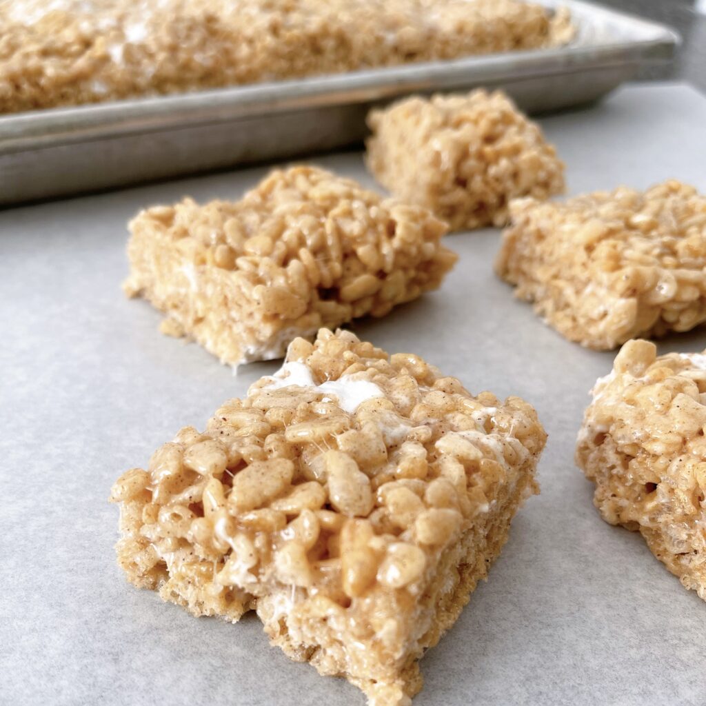 Pumpkin Rice Krispie treats cut into squares on parchment paper.