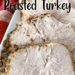 Slices of butter & herb roasted turkey on a white plate.
