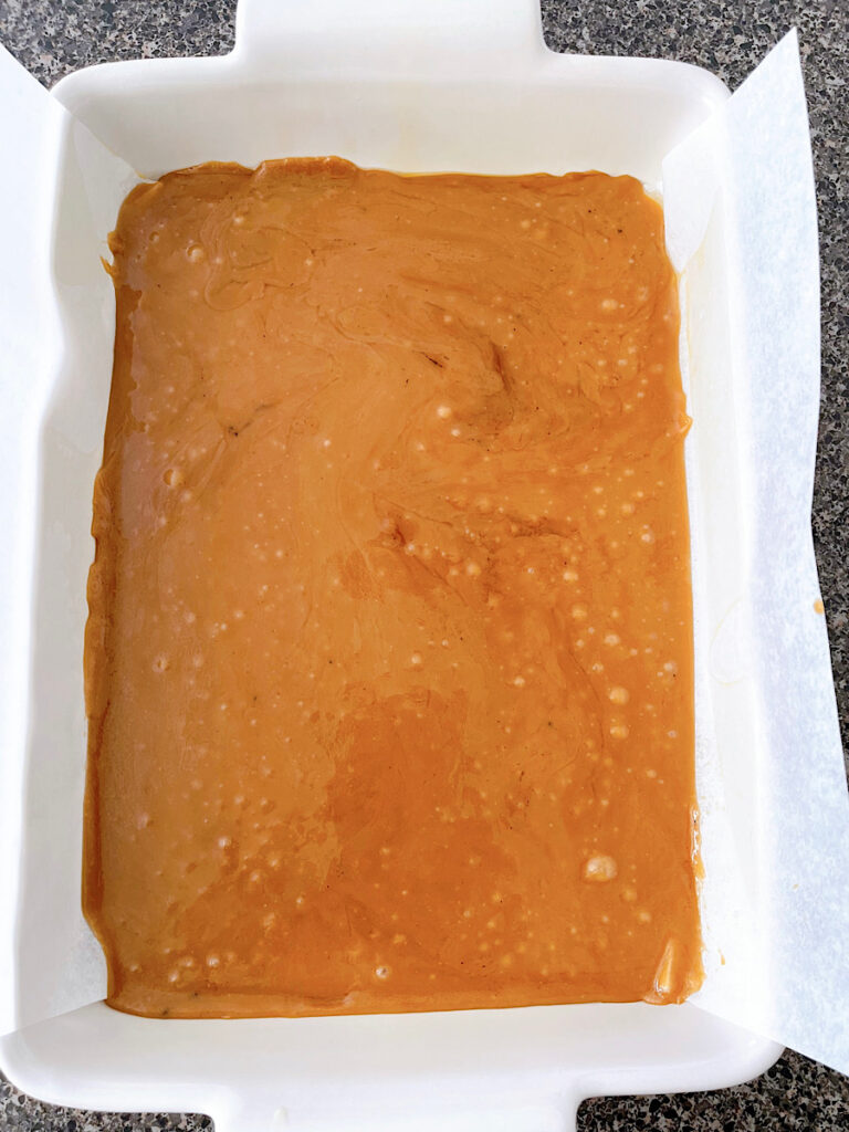 Toffee in a white baking sheet lined with parchment paper.