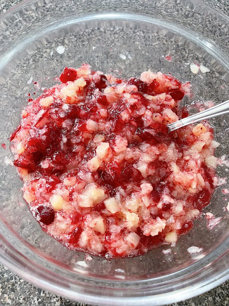 A bowl of cranberry sauce mixed with crushed pineapple.