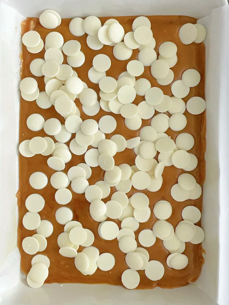 White chocolate candy melts on a pan of toffee.