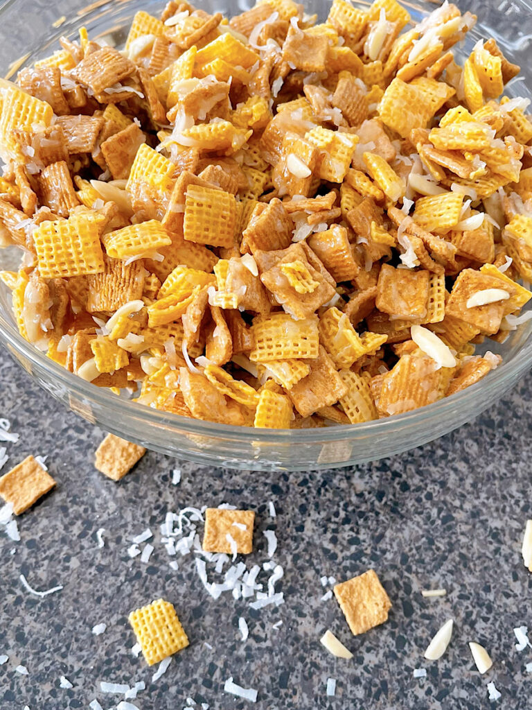 A bowl of Christmas Chex Mix with Golden Grahams, Chex, coconut, and almonds.