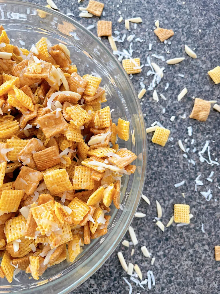 A bowl of Christmas Chex Mix with Golden Grahams, Chex, coconut, and almonds.