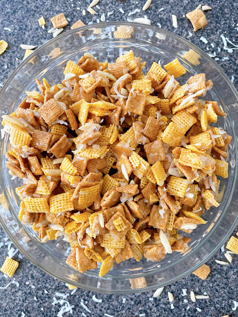 A bowl of Christmas Chex Mix with Golden Grahams, Chex, coconut, and almonds.