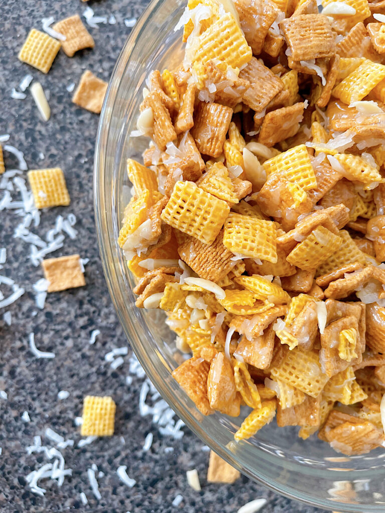 A bowl of Christmas Crack Chex Mix with Golden Grahams, Chex, coconut, and almonds.