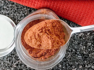 Homemade pumpkin spice on a spoon over a jar.