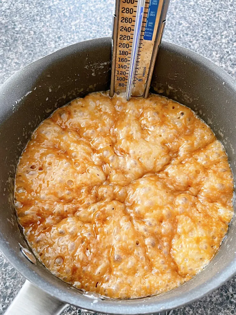 Butter and sugar melted in a pan with a candy thermometer to make churro toffee.