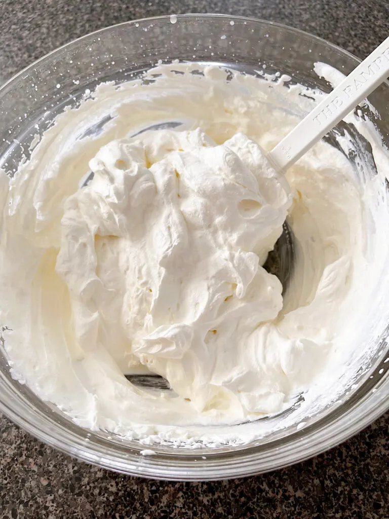 A bowl of whipped cream mixed with cream cheese and sugar.
