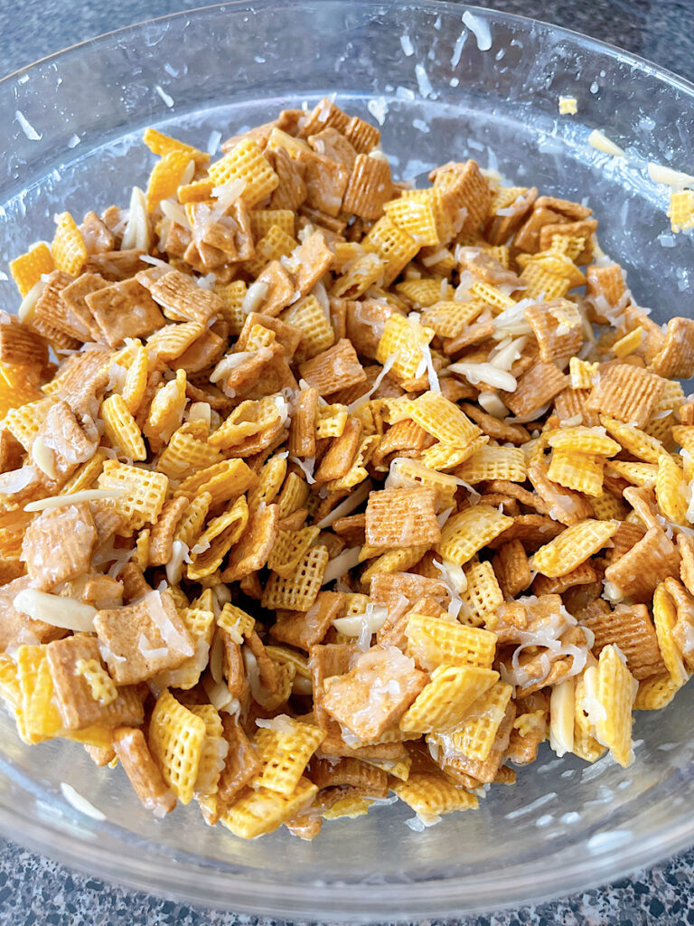 A bowl of Christmas Chex Mix with Golden Grahams, Chex, coconut, and almonds.