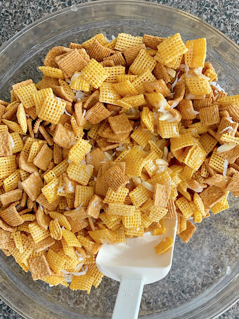 A bowl of Christmas Chex Mix with Golden Grahams, Chex, coconut, and almonds.