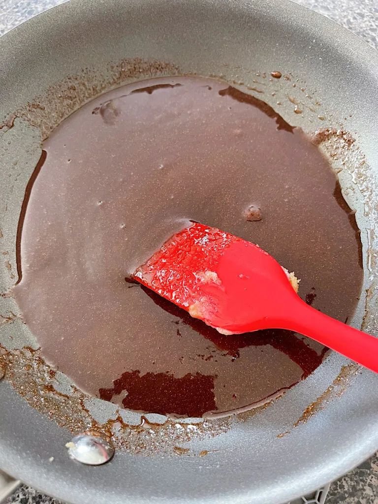 Cinnamon roll filling in a pan with a spatula.