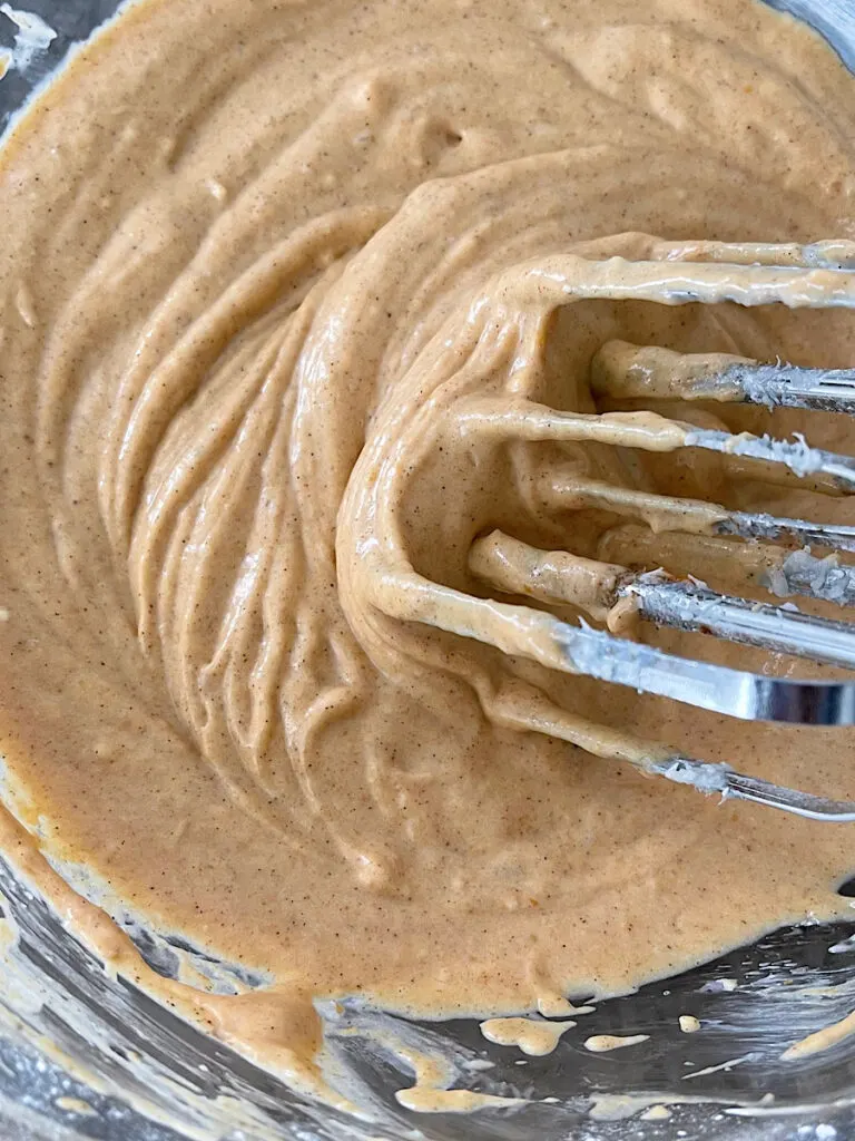 Pumpkin pie dip in a mixing bowl with a hand mixer.