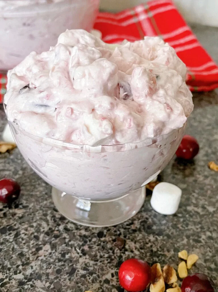 A bowl of cranberry fluff salad with marshmallows and walnuts.