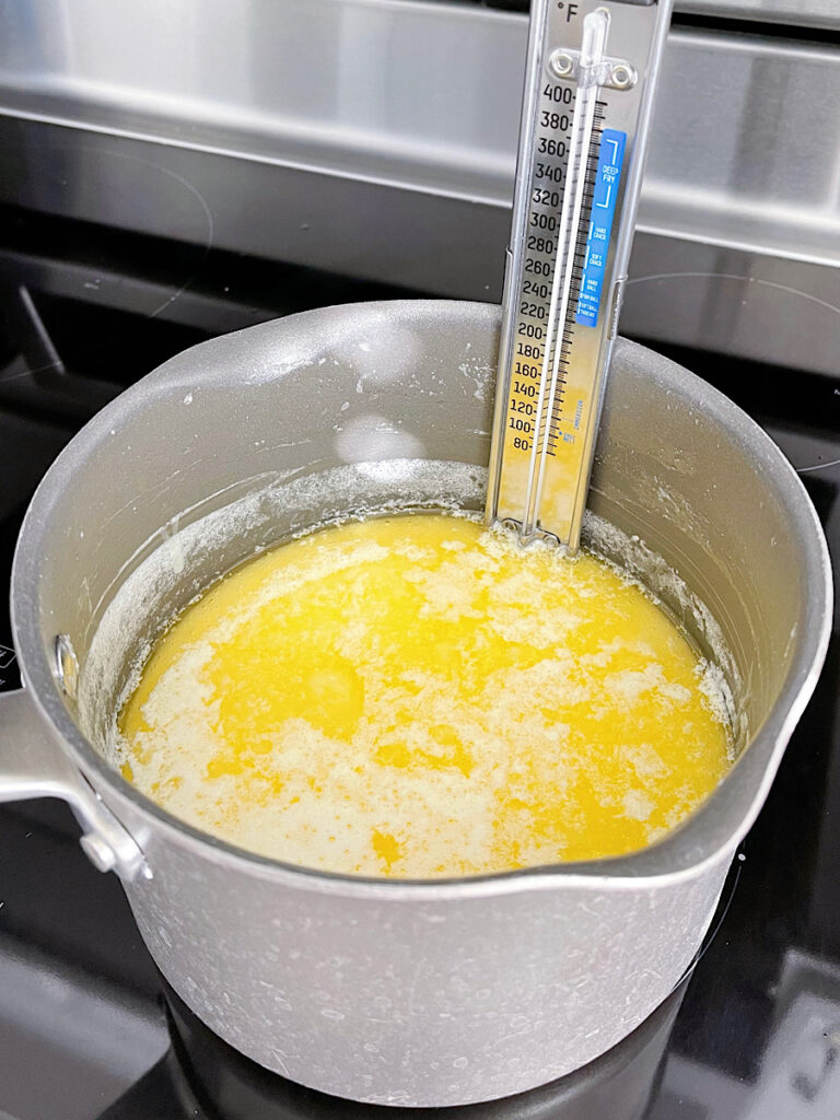 Butter and sugar in a pan with a candy thermometer to make toffee.