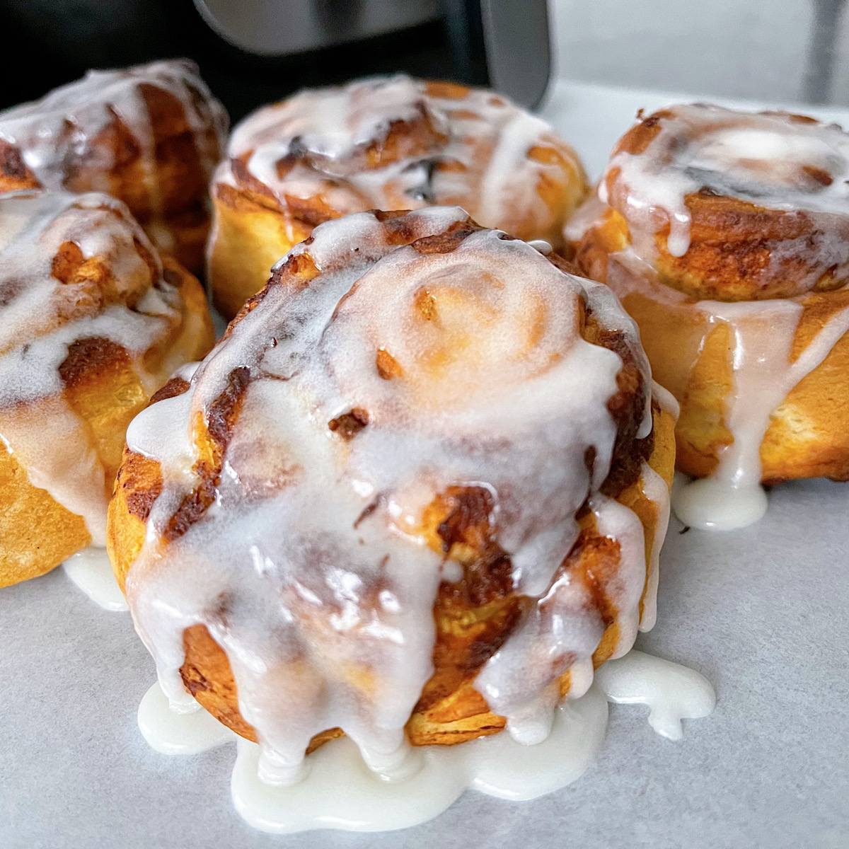 Pillsbury Air Fryer Cinnamon Rolls in front of an air fryer.