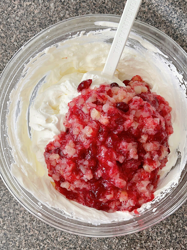 Cranberry sauce in a bowl of whipped cream and cream cheese.