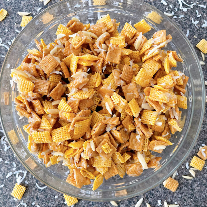 A bowl of Christmas Crack Chex Mix with Golden Grahams, Chex, coconut, and almonds.