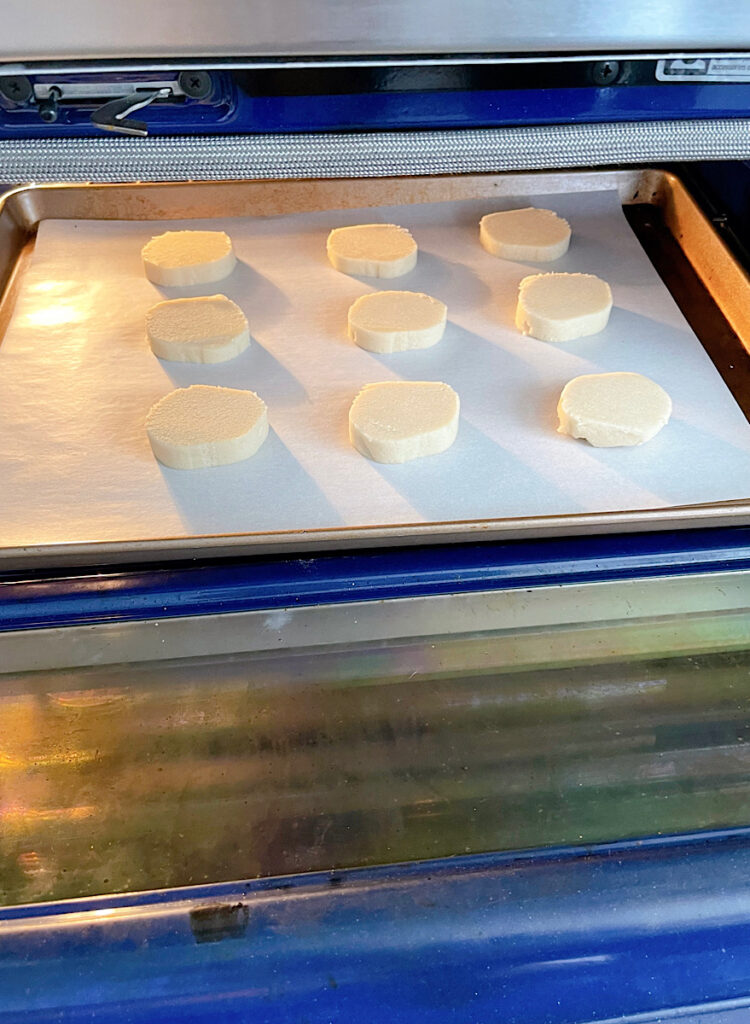 Sugar cookies on a baking sheet in an oven.