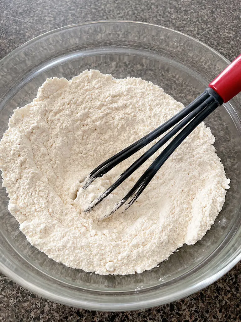 Dry ingredients for sweet cream pancakes in a mixing bowl with a whisk.