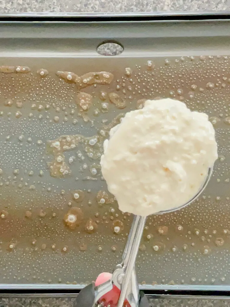 Pancake batter in a scoop over a griddle.