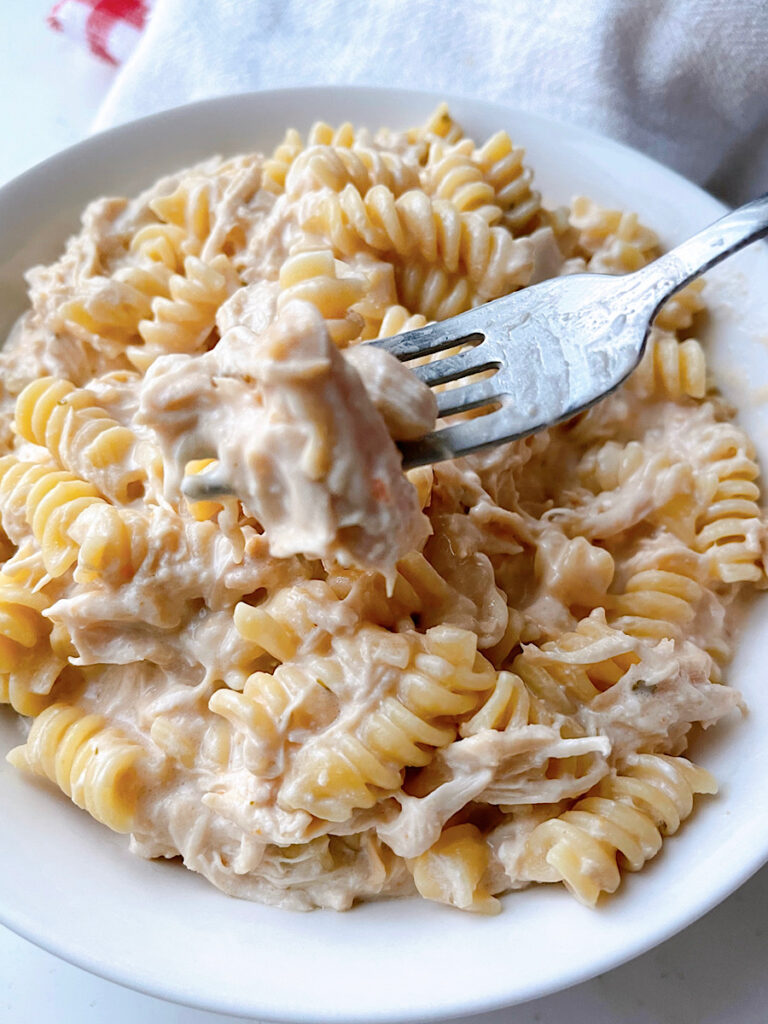 A bowl of chicken pasta and a bottle of Olive Garden Salad Dressing.