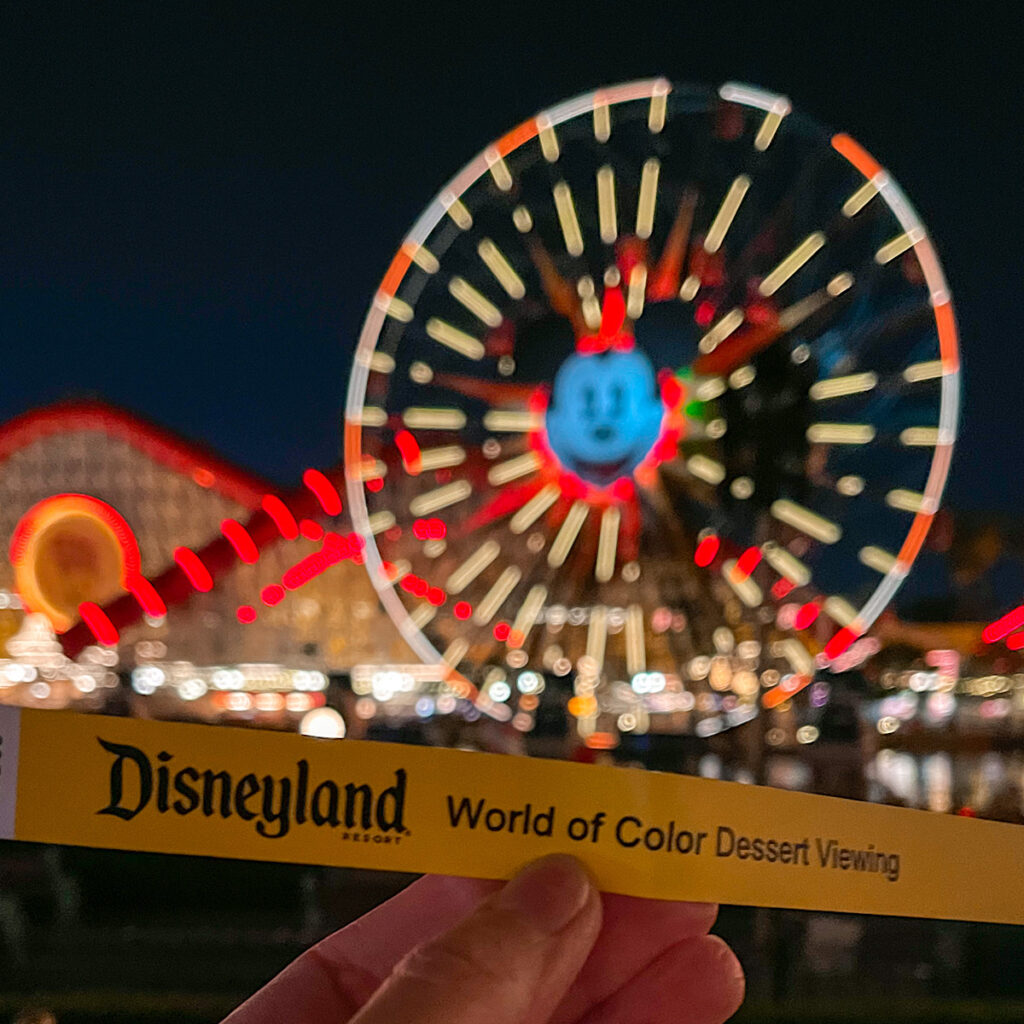 A bracelet for World of Color Dessert Party in front of the Mickey ferris wheel at Disneyland.