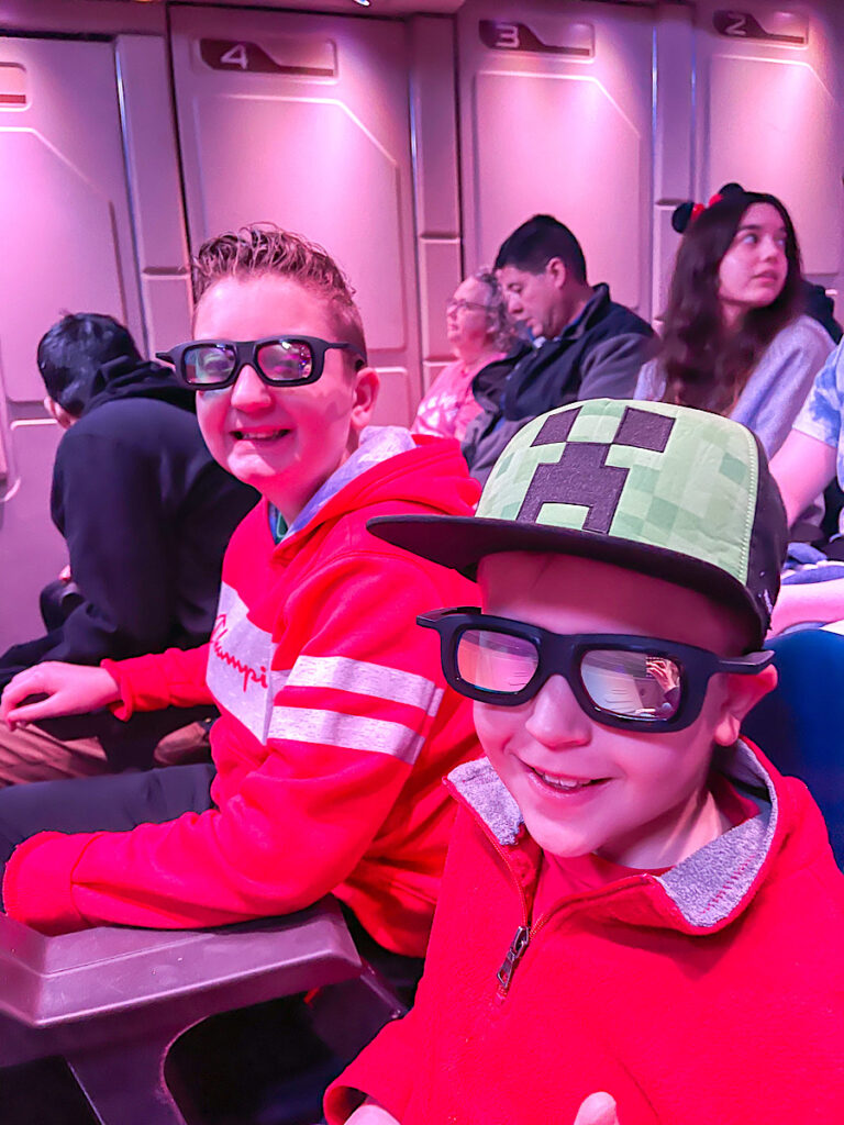 Two kids with 3D glasses ready to ride Star Tours at Disneyland.