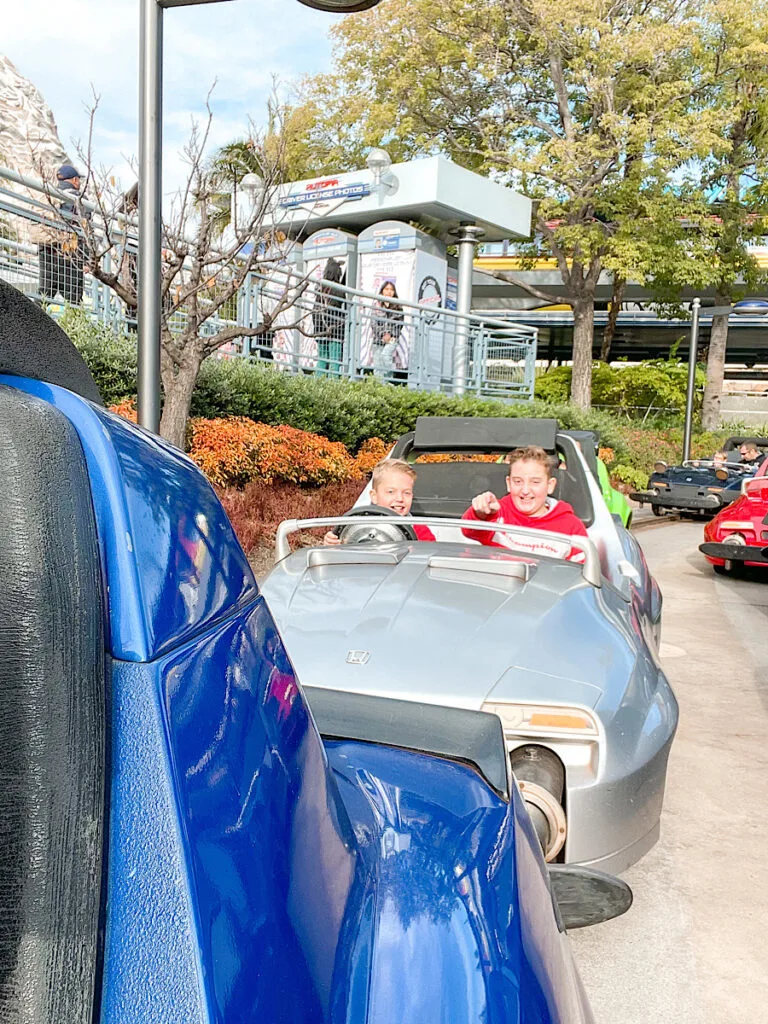 Two kids in a car riding Autopia at Disneyland.