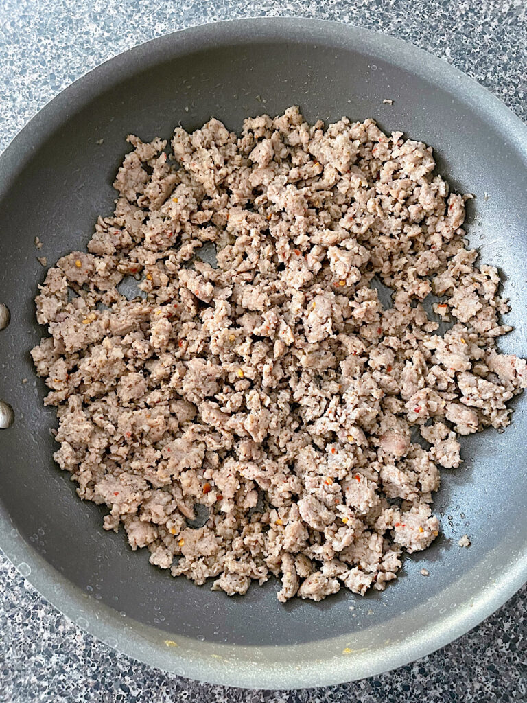 Browned ground sausage in a frying pan.