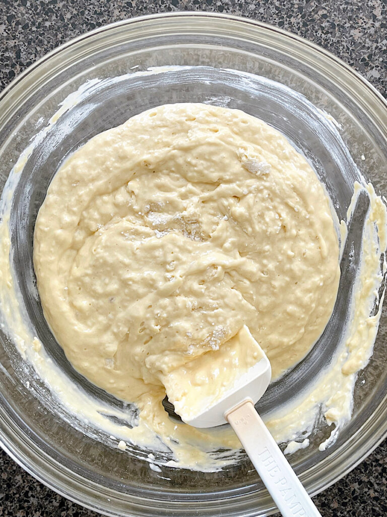 Sour cream pancake batter in a glass mixing bowl.