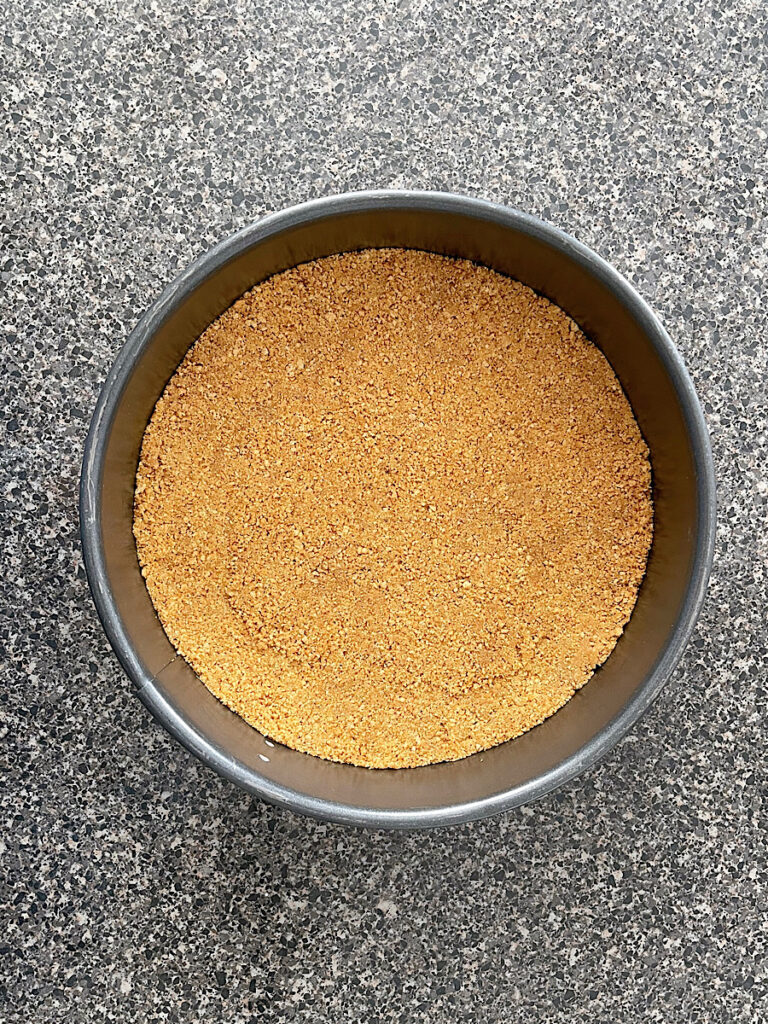 Graham cracker crumbs pressed into the bottom of a springform pan.