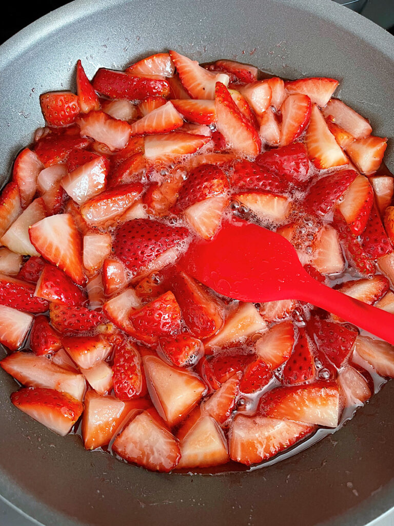 Strawberry compote boiling in a saucepan.