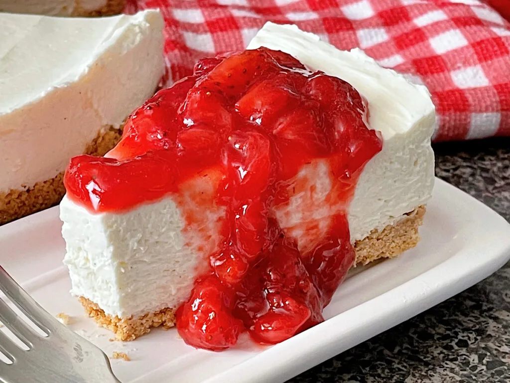 A slice of Philadelphia No Bake Cheesecake with strawberry sauce.