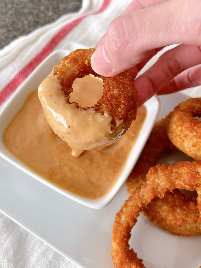 A Red Robin onion ring dipped in Campfire Sauce.