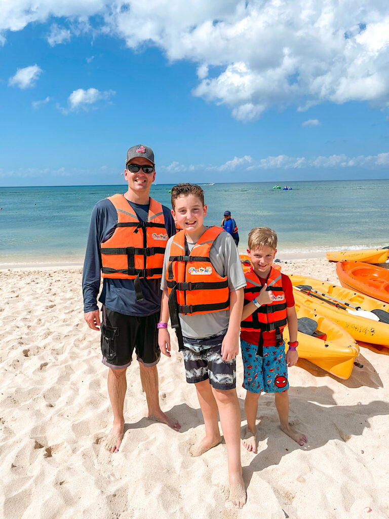A dad and two kids next to kayaks at Playa Mia a Disney Cruise Cozumel Beach Break excursion.