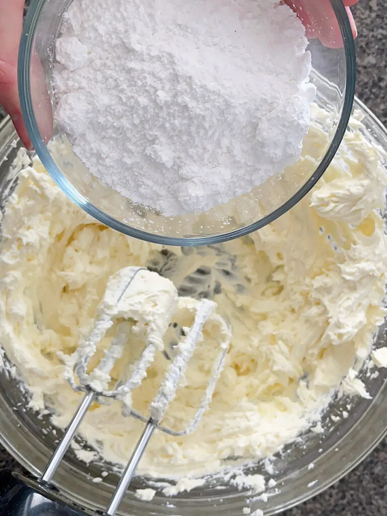 Powdered sugar over a bowl of whipped cream cheese.