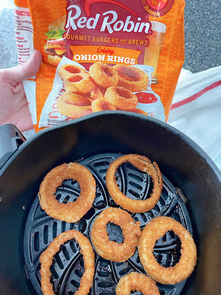 Frozen Red Robin onion rings in an air fryer basket.