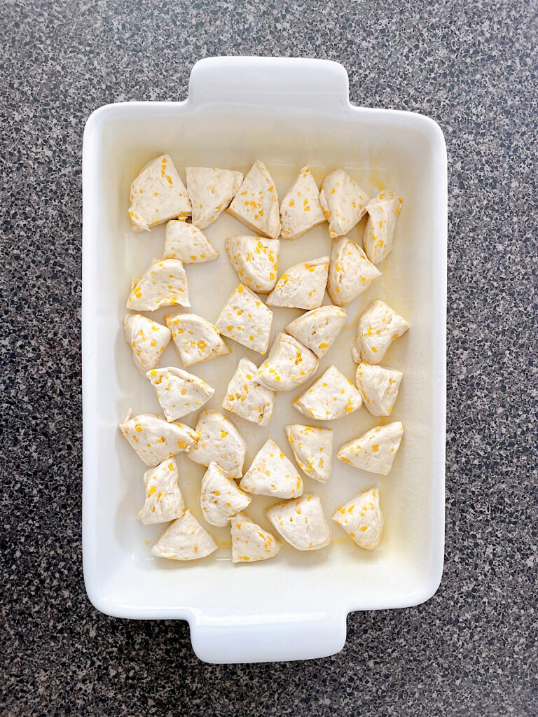 Refrigerated biscuits cut into fourths spread into a baking dish.