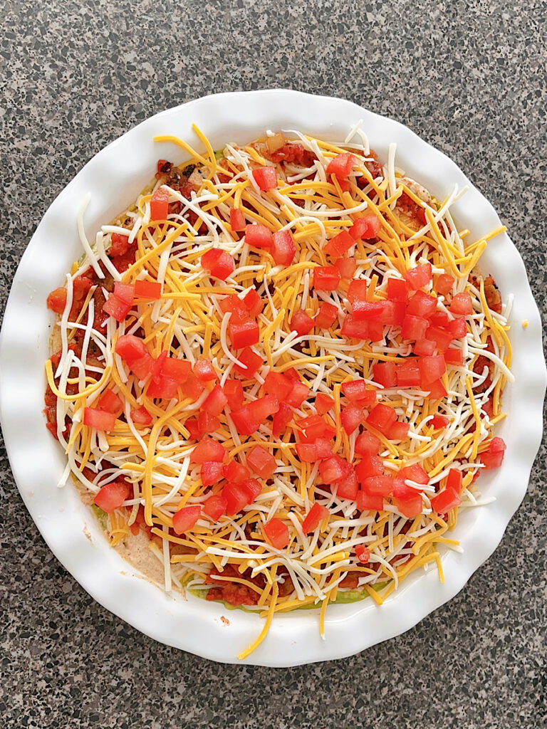 Tomatoes sprinkled on top of seven layer dip.